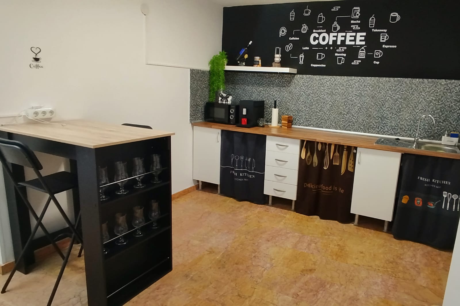 Espacio de cocina y descanso con barra alta, taburetes y zona de preparación en Tecni Estudio Coworking