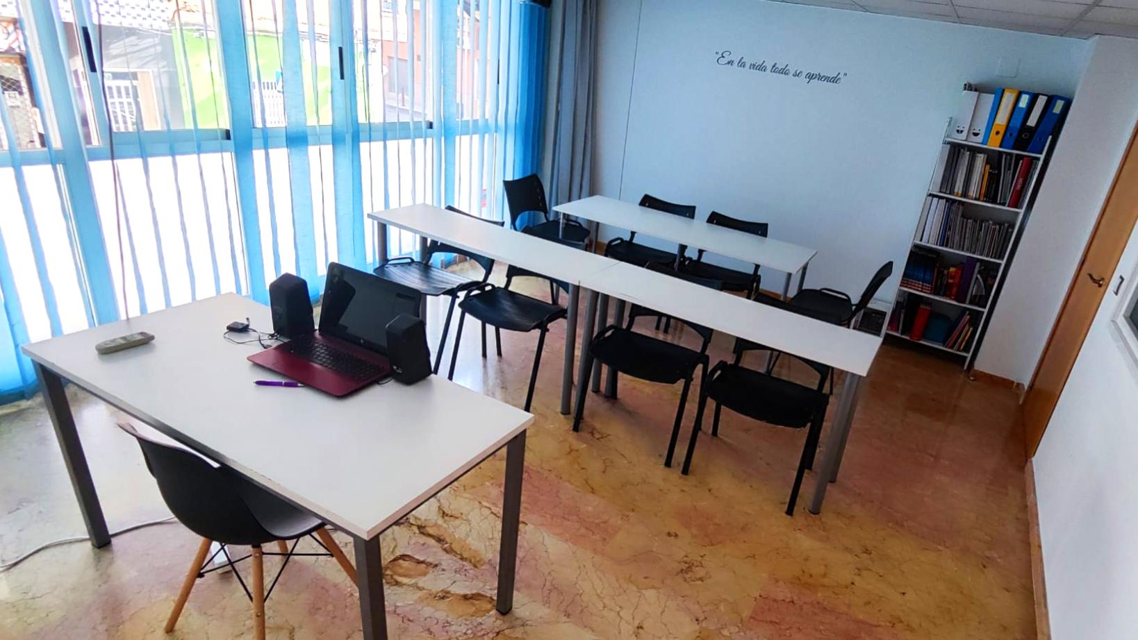 Aula de formación en Tecni Estudio equipada con mesas, sillas y proyector.